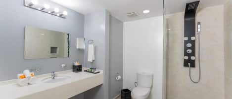 A modern bathroom with two sinks, a large mirror, a glass shower enclosure, and a toilet.