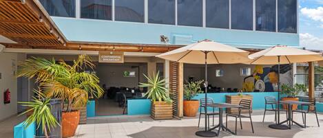 An outdoor cafe area with tables and chairs, potted plants, and a sign for continental breakfast.