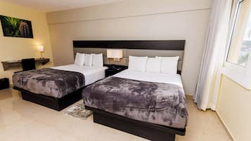 Quarto de hotel com duas camas, uma escrivaninha e uma mesa de cabeceira.