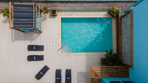 Un espace piscine aménagé sur le toit, comprenant un jacuzzi, des chaises longues et un petit coin salon.