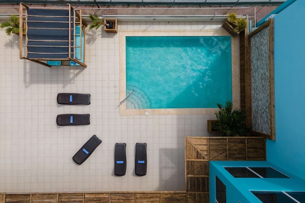 Uma área de piscina no terraço com hidromassagem, espreguiçadeiras e um pequeno espaço para sentar.