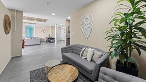 Un salon moderne avec un canapé gris, une table basse ronde en bois et une plante en pot.