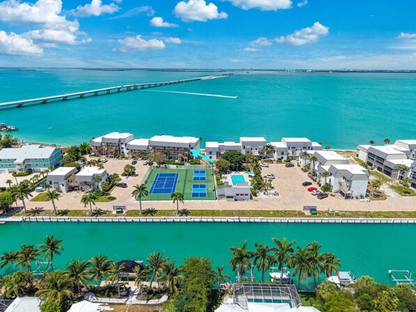 Um hotel à beira-mar com vários edifícios, quadra de tênis e área de piscina.
