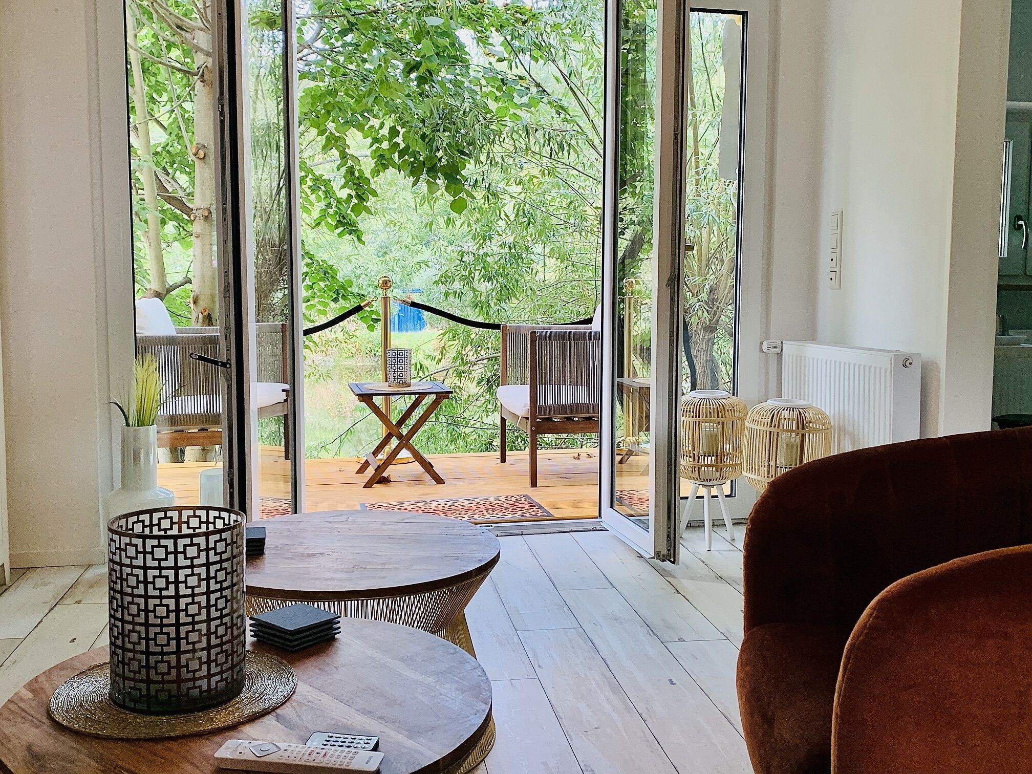 A room with a large sliding glass door leading to an outdoor area with a wooden deck, chairs, and a table.