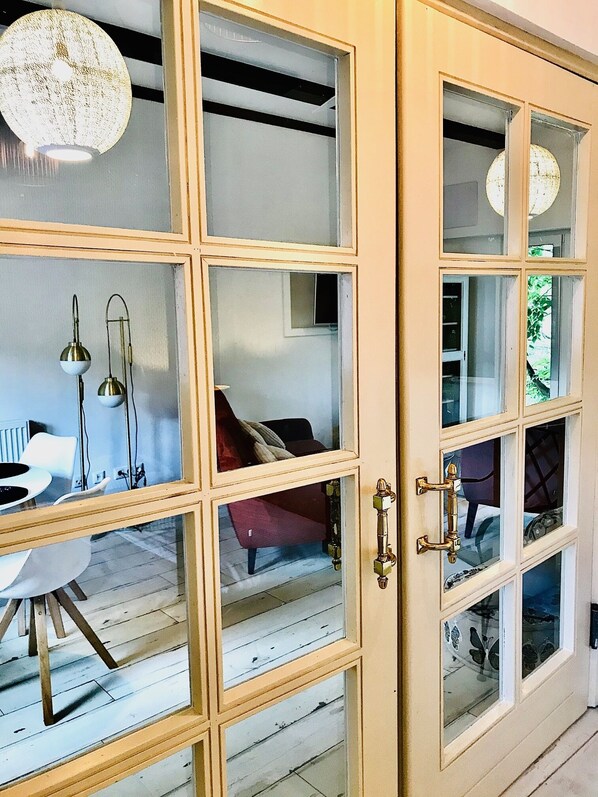 A room with a large cabinet with multiple glass doors, a dining table with chairs, and a hanging light fixture.