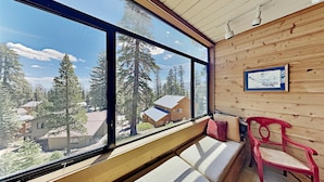 Une cabane dotée de grandes fenêtres donnant sur une forêt et d’autres cabanes.