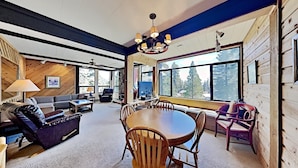 L’intérieur chaleureux d’un chalet comprend une table à manger, des chaises, un canapé et un téléviseur.
