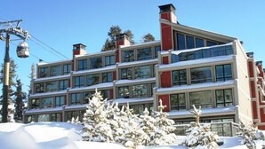 Un hôtel à plusieurs étages, doté de grandes fenêtres, avec un télésiège visible en arrière-plan.