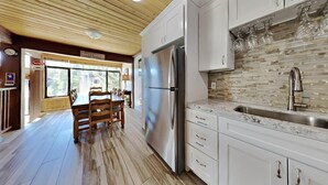 A modern kitchen with white cabinets, a stainless steel refrigerator, and a tiled backsplash. - Spacious 2 Bedroom Condo Great For Friends and Families! Hiking, Swimming, Stargazing! by RedAwning (Mammoth Lakes)