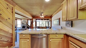 Une cuisine spacieuse avec des meubles en bois, un plan de travail en granit et un lave-vaisselle encastré.