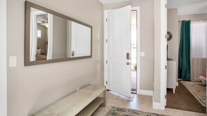 Un pasillo con un banco, un espejo grande y una puerta que da a otra habitación.