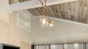 Une pièce avec un plafond en bois, un téléviseur fixé au mur et un meuble en bois doté de tiroirs.