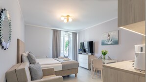 A modern hotel room with a bed, sofa, desk, and kitchenette. - Ferienwohnung am Meer, Urlaub auf der Insel Usedom, Appartement Pegaz 10 (Swinoujscie)
