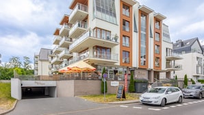 A multi-story building with a restaurant on the ground floor, outdoor seating, and a parking area. - Ferienwohnung am Meer, Urlaub auf der Insel Usedom, Appartement Pegaz 10 (Swinoujscie)