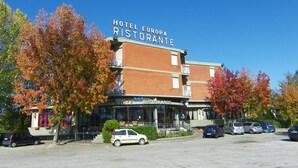 Um hotel chamado "Hotel Europa Ristorante", com estacionamento e árvores de folhagem outonal.