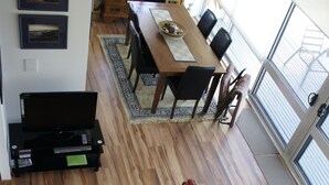 Un vaste espace de vie doté d’un plancher en bois, d’une table à manger et d’un meuble pour la télévision.