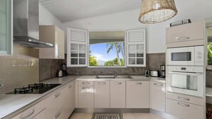 A modern kitchen with a large window, built-in appliances, and a kitchen mat. - Nature Paradise - Four Bedroom Villa, Sleeps 8 (Rivière-Pilote)