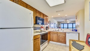 A kitchen with wooden cabinets, a white refrigerator, a microwave, and a dishwasher.