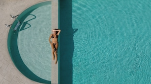 An aerial view of a swimming pool with a person lying on the edge.