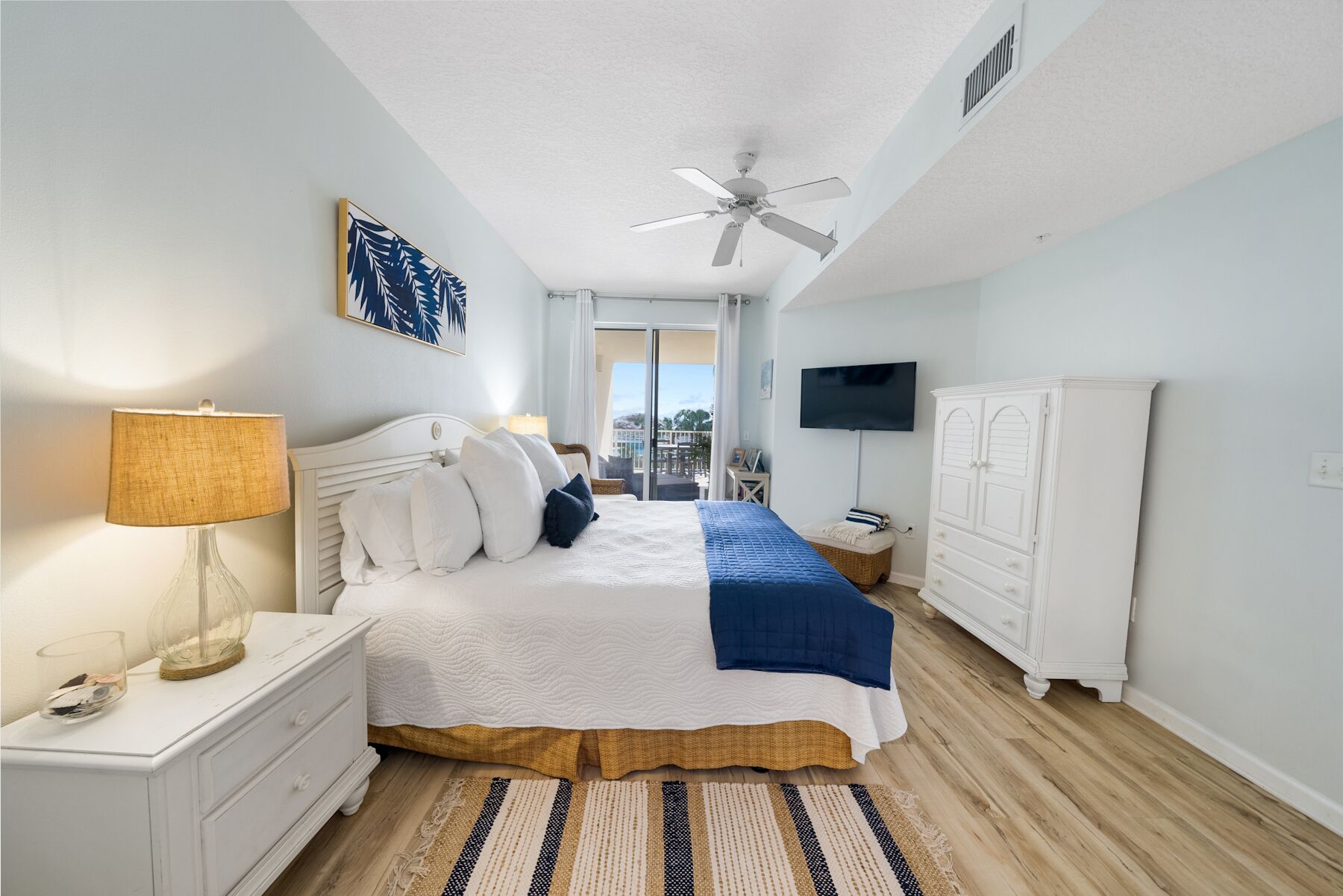 A bedroom with a bed, bedside tables, a TV, a wardrobe, and a view of the outdoors.