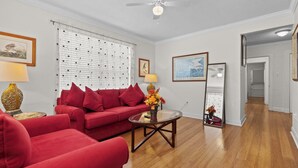 Un salon avec un canapé rouge, une table basse en verre et un ventilateur de plafond.