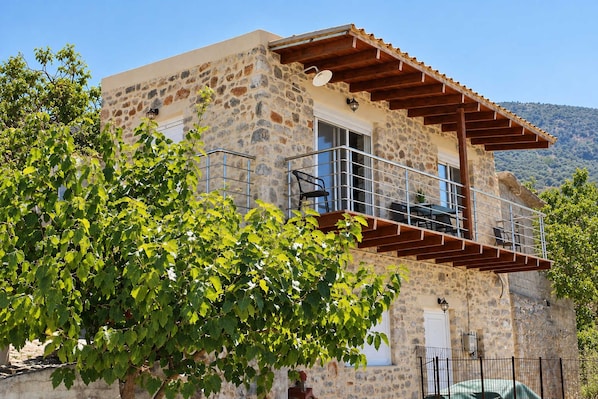 A stone building with a balcony, a satellite dish, and a view of the hills.