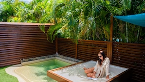 Zona de spa con jacuzzi, terraza de madera y abundante vegetación.