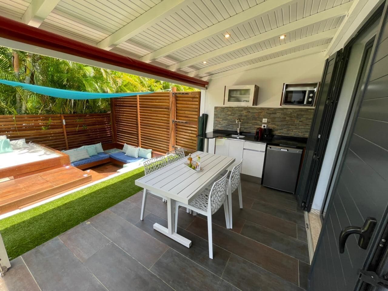 A modern outdoor kitchen with a dining area, a TV, and a microwave.
