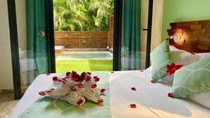 Una habitación de hotel con una cama, cortinas verdes y vistas a un jardín.