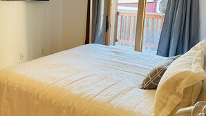 A bedroom with a bed, a flat-screen TV mounted on the wall, and a balcony with curtains. - Premier Downstairs Flat in Perfect Down Town Location  (Ashland)