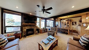 Cozy living room with a fireplace, comfortable seating, and a large window offering a view of the outdoors.