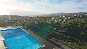 A swimming pool with a view of a residential area and hills in the background.