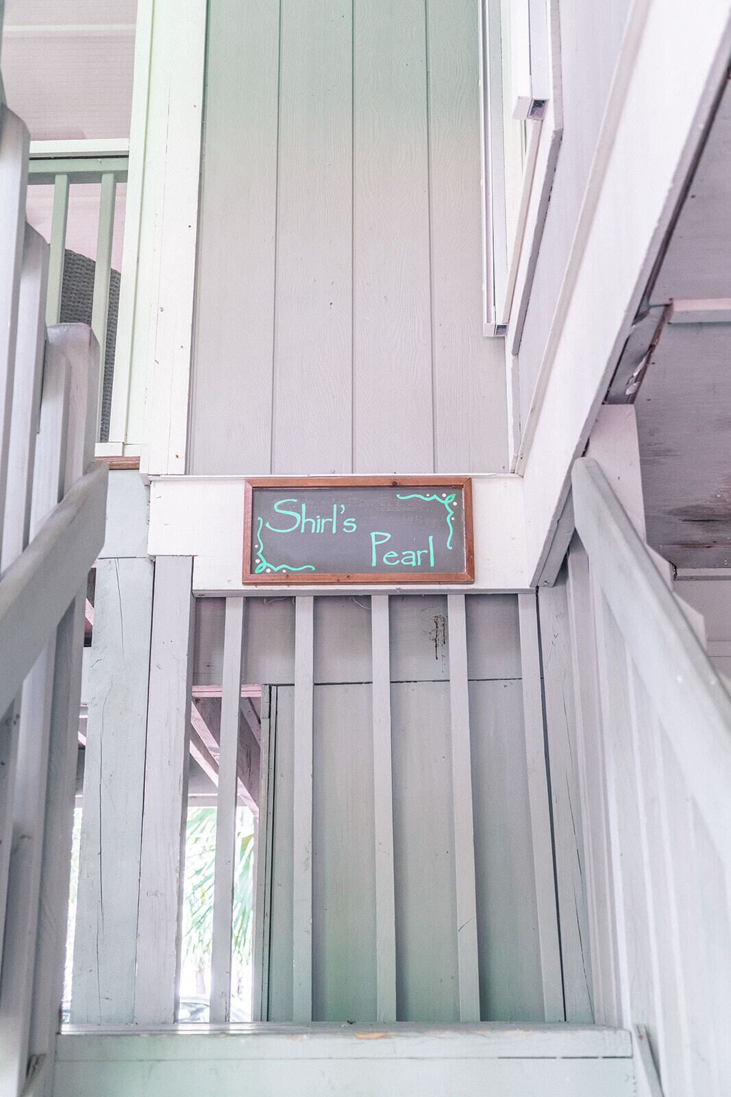 Une pancarte sur un escalier portant l’inscription : « Shirl’s Pearl ».