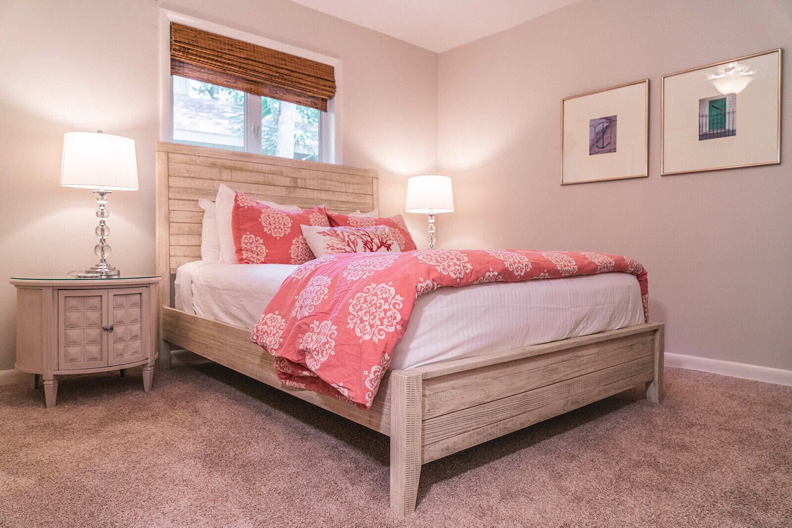 A bedroom with a wooden bed, two bedside lamps, a nightstand, and a window with blinds.