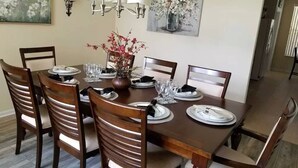 A dining table set with plates, glasses, and a vase of flowers. - Spacious Luxurious 6 Bedroom 5 Bath Villa Sleeps 12 Pool, Jacuzzi, near Disney (Kissimmee)