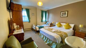 Hotelkamer met een bed, bureau, stoel, bureaulamp, nachtkastje, spiegel, raam met gordijnen, een foto aan de muur en een wastafel.