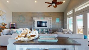 Un salon comprenant un téléviseur, des canapés, une table basse et une horloge murale décorative.