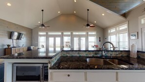 A spacious kitchen with a large island, a microwave, and a sink. - Salty Waves: 3  BR, 2  BA House in Port Bolivar, Sleeps 12 (Bolivar Peninsula)