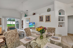Relax in this spacious living room with a dining area for six, comfortable seating, and a large window offering a view of the outdoor area.