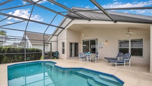 An indoor swimming pool with a glass ceiling, a covered patio with chairs, and a view of a house in the background. - No Rear Neighbors, Near Disney Spacious Home With CDC Standards #3hr836 (Davenport)