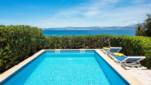 A swimming pool with lounge chairs and a view of the sea. - Beachfront twin villa, private heated pools and amazing sea views - Villa Violet (Supetar)