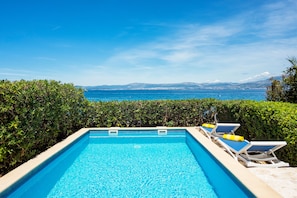 Une piscine avec des chaises longues et vue sur la mer.