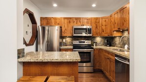 A kitchen with wooden cabinets, stainless steel appliances, granite countertops, and a built-in oven.
