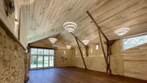 Une pièce spacieuse dotée de planchers en bois et de plafonds inclinés, avec des luminaires intégrés et de grandes fenêtres.