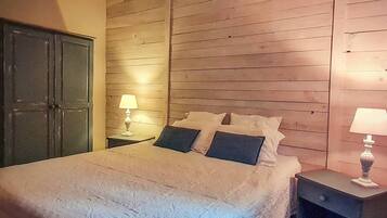 Une chambre à coucher avec un grand lit, des lambris en bois sur les murs, deux tables de chevet avec des lampes et une armoire.