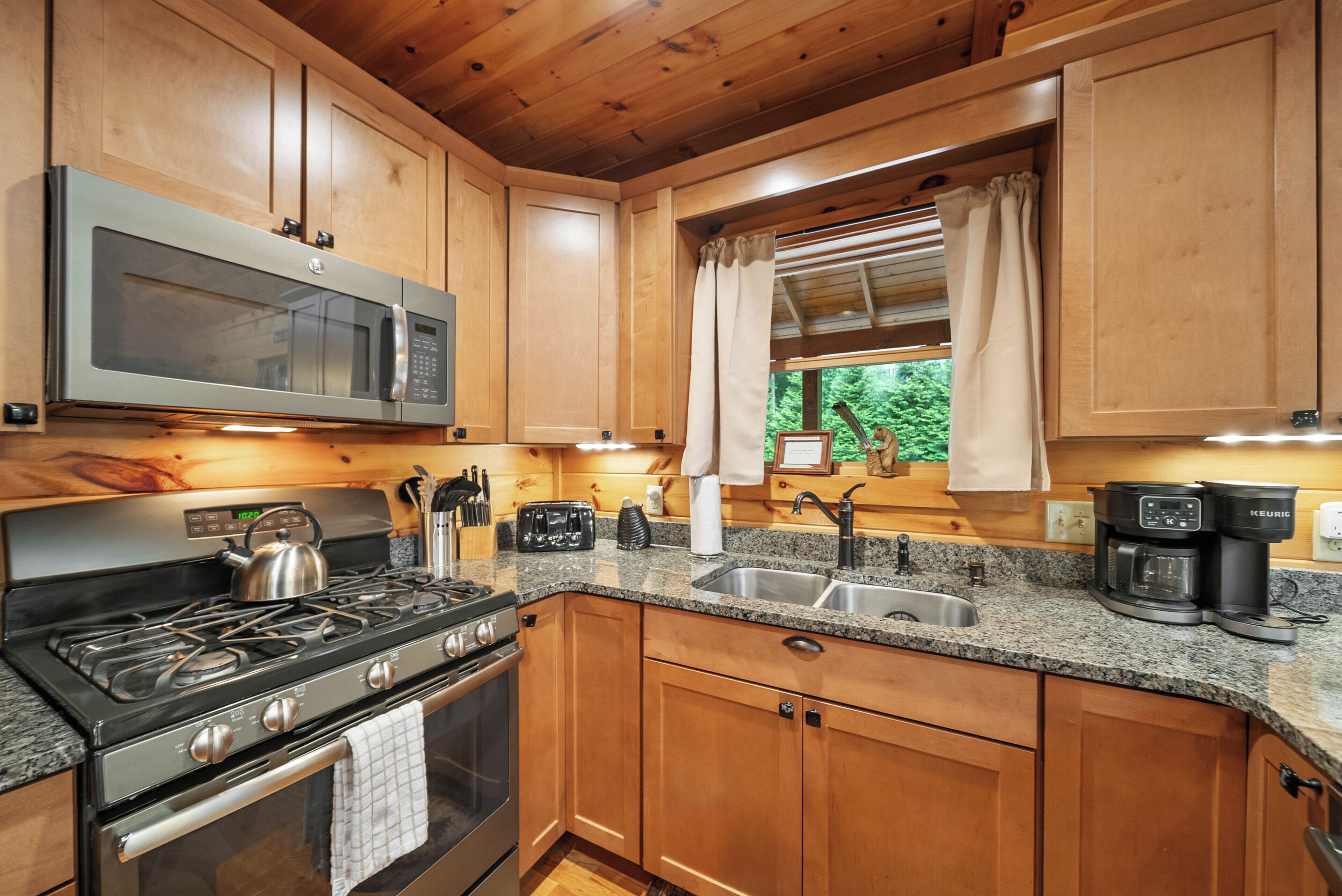 A modern kitchen with wooden cabinets, stainless steel appliances, a gas stove, a microwave, and a coffee maker.