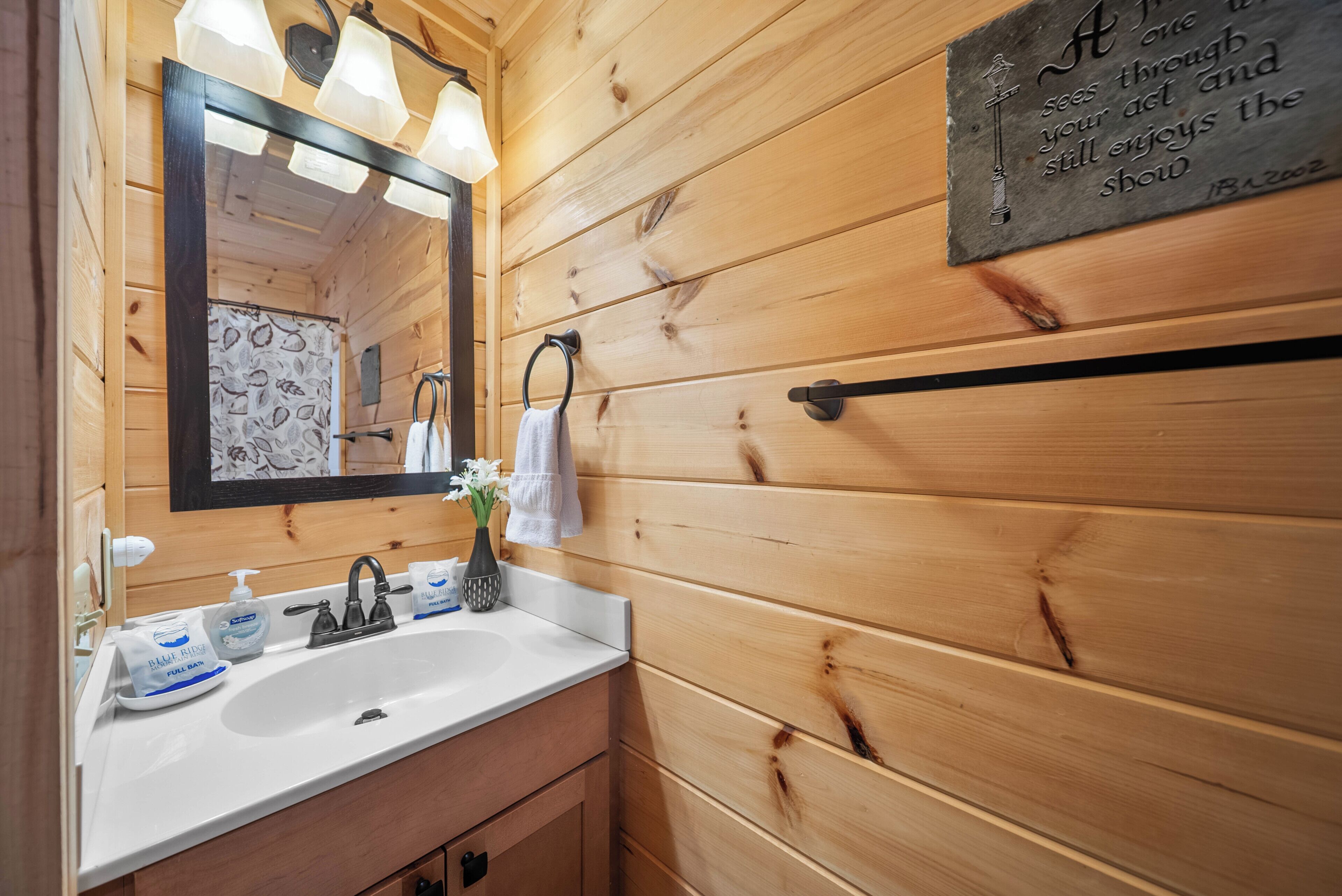 A wooden-paneled bathroom with a white sink, a mirror, and a towel rack.