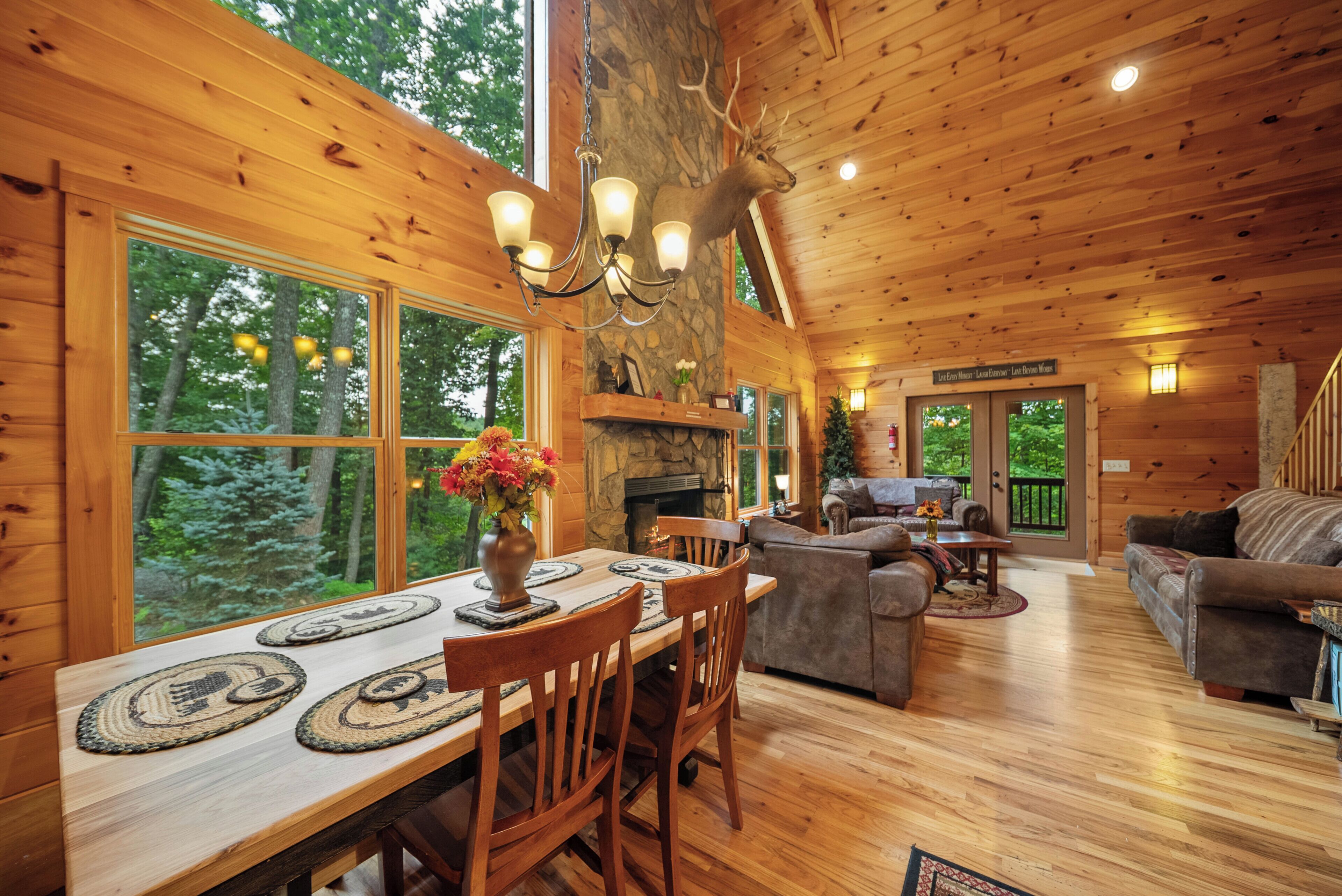 L’intérieur d’un chalet en bois comprend une table à manger, des chaises, une cheminée et un coin salon avec un canapé et une table basse.