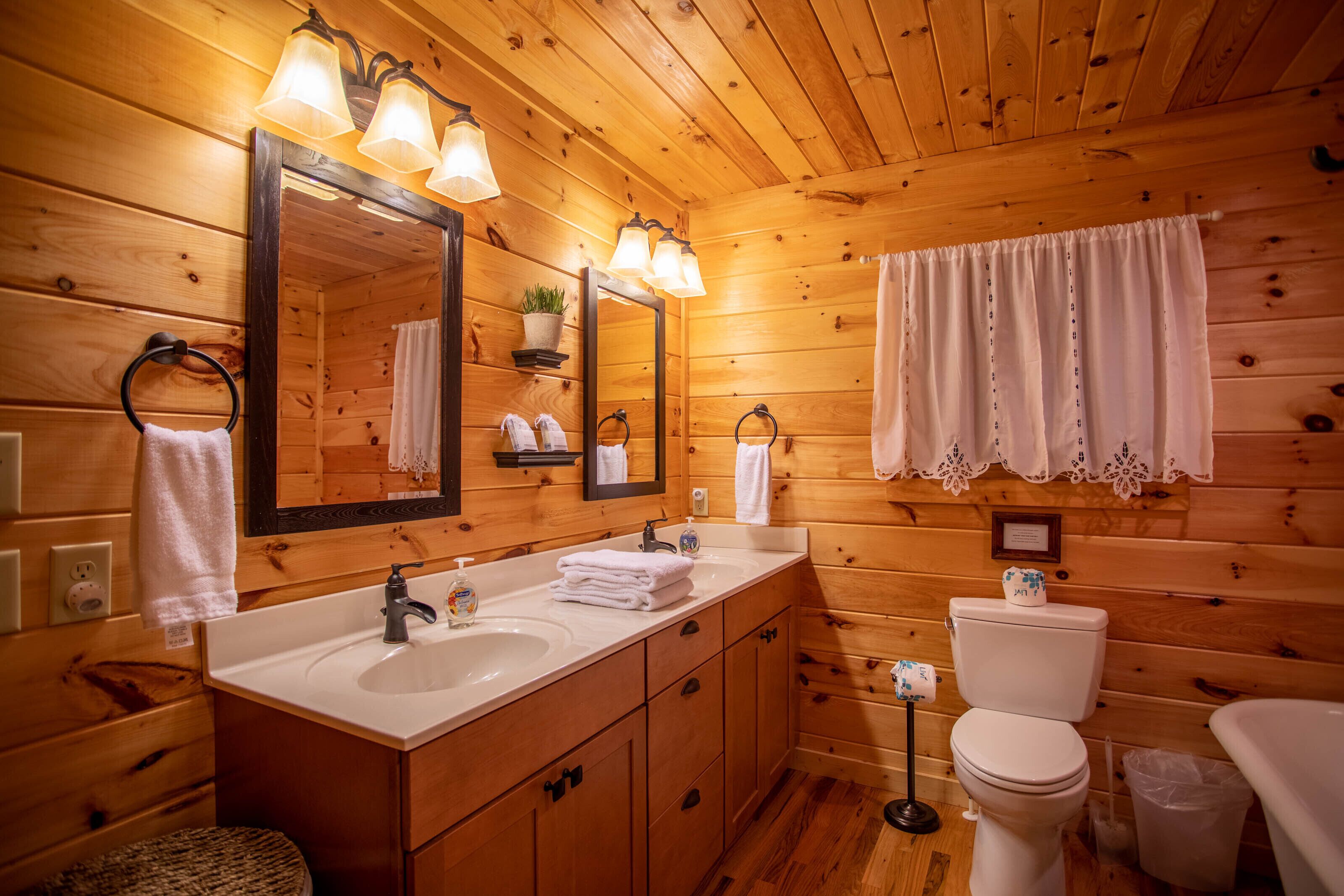 Een houten badkamer in een chalet, met een wastafel, spiegel, toilet en een handdoekhouder.