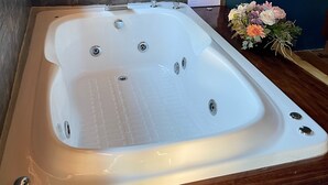 Un jacuzzi grande y rectangular con múltiples chorros, frente a una pared azul oscuro con detalles de piedra.